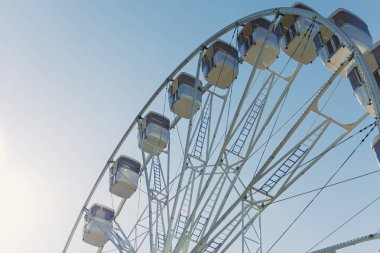 Şehri yukarıdan seyretmek için bir cazibe. Mavi gökyüzüne karşı kamaraları olan büyük bir dönme dolap havalanıyor. Kapalı kamaralı bir dönme dolap..
