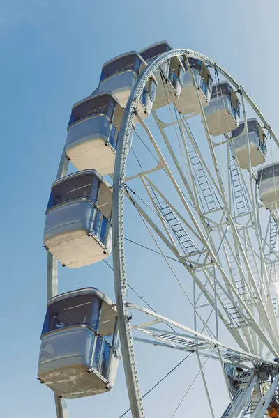 Mavi gökyüzüne karşı kamaraları olan büyük bir dönme dolap havalanıyor. Etrafı kapalı bir dönme dolap..