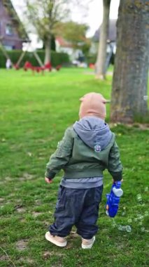 Panama giymiş küçük bir çocuk oyun alanında koşuyor ve oynuyor. Neşeli 2 yaşındaki çocuk güneşli bir günde dışarıda oynuyor..