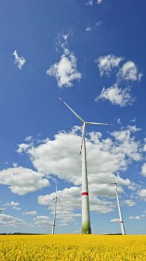 Rüzgar türbinlerindeki eko-enerji alanı. Alternatif enerji türbinleri ve mavi gökyüzünün arka planında bıçaklar. Rüzgar çiftliği ağır çekim. Yel değirmenlerinin siluetleri.