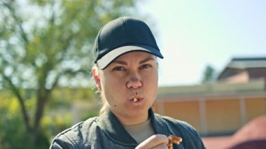 Sokakta duran ve Belçika waffle 'ı yiyen genç bir kadın. Atıştırmalık temiz hava. Sokakta lezzetli hamur işleri yiyen bir kadın. Tatlı sokak yemekleri..