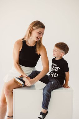 Anne ve 4 yaşındaki oğlu beyaz bir arka planda gülümsüyor ve sarılıyorlar. Anne ve oğul arasındaki sıcak ilişki. Anne ve oğul arasındaki aile ilişkileri kavramı.