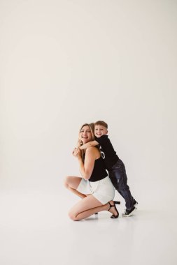 Beyaz arka planda otururken kucaklaşan tatlı anne ve bebek. Mutlu anne ve oğul, babalarının işten dönmesini bekliyorlar. Anne ve oğlunun eğlenceli oyunları..