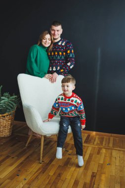 Renkli tatil kazakları içinde canlı bir aile, neşeli bir şekilde birlikte poz verir. Şenlik sezonunun sıcaklığını ve ruhunu şık ve rahat bir atmosferle somutlaştırırlar.