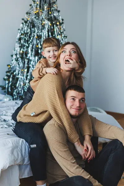 Güzel dekore edilmiş bir Noel ağacının etrafındaki bayram mevsimini kutlarken neşe ve kahkahalarla dolu yürek ısıtan bir aile anı.