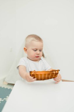 Renkli oyuncaklarla dolu neşeli bir oyun odasında, kısa sarı saçlı bir çocuk dikkatle bir oyuncağı keşfeder, yaratıcılıklarını arttırır ve çocukluk sevincini yansıtır.