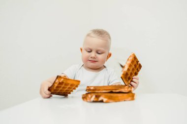 Neşeli bir ortamda, neşeli bir çocuk lezzetli waffle 'lardan zevk alır, erken çocukluğun saf neşesini ve gülümseme getiren basit zevkleri somutlaştırır.