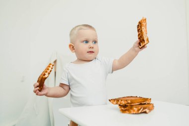 Sevimli, modern bir mutfak ortamında, sevimli bir bebek zevkle lezzetli bir yığın waffle tutar, bir anlık keşif ve saf neşe, aile içeriği için mükemmeldir.