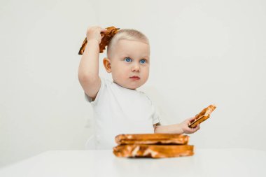 Sıcak bir ortamda, mutlu bir bebek çıtır kraker atıştırmalıkları tutar, kalıcı anılar yaratan eğlenceli aile projelerine ilham verir ve lezzetli anları paylaşmanın sevincini vurgular.