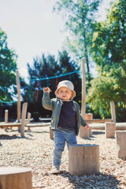 Neşeli bir çocuk, bu güzel günde sıcak güneşin tadını çıkarırken sağlam bir tahta kütüğün üzerinde kendinden emin bir şekilde duran, doğuştan gelen bir oyun alanını keşfeder.