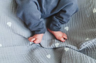 Narin küçük bebek ayakları yumuşak gri bir battaniyeye nazikçe istirahat eder. Güzel kalp şekilleriyle süslenir. Masumiyetin ve sıcaklığın özünü güzel bir şekilde yakalar.