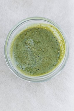 Canlı yeşil bir bitkisel sos temiz bir cam kabın içinde güzelce sergilenir ve çeşitli lezzetli yemeklerin lezzet profilini geliştirmek için ideal bir ilave olur.