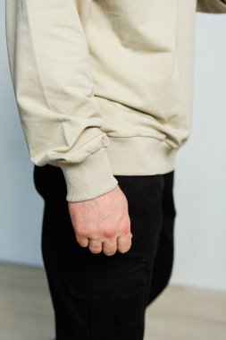 İşte bir insanın el ve kolunun yakın çekimi, nötr renklerden oluşan modern, rahat bir kıyafeti vurguluyor, günlük kıyafet ve stil için mükemmel