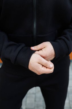 Bu yakın plan görüntüde, şık siyah spor kıyafetleri giymiş, zarif katlanmış elleriyle, dikkat çekici bir görsel etki yaratan sakin bir güven yayar.