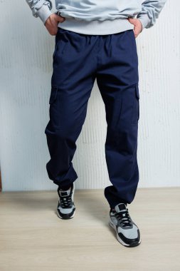 Erkek donanması pantolonları ve şık spor ayakkabıları modern bir arka plana karşı şık ve sıradan bir görünüm yaratıyor, zahmetsizce modaya uygun bir görünüm sergiliyor.