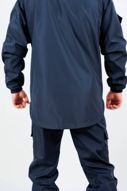 Görüntü, hem açık hava aktiviteleri hem de profesyonel ortamlar için ideal, koyu renk deniz geçirmez ceketli ve uyumlu pantolonlu bir kişiyi gösteriyor.