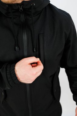 Bu resim, moda veya yaşam tarzı temaları için mükemmel, eşsiz desenli siyah bir fermuar ceketi ayarlayan bir kişinin yakın çekimini içerir.