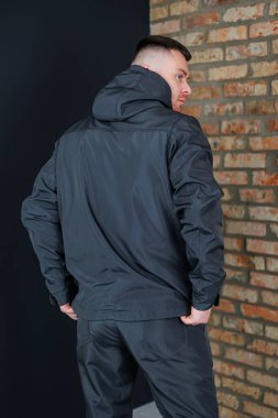 Gösterişli siyah ceketli ve şık pantolonlu modern bir adam şehir ortamında, modern modayı yansıtan modaya uygun, modaya uygun bir açık hava kıyafetini sergiliyor.