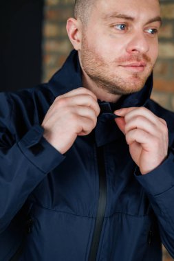 Şık bir genç adam şık bir donanma ceketi giyer ve sanayi stili bir ortamda özenle ayarlar. Bu da inkâr edilemez karmaşıklığı ve kendine güvenini gösterir.