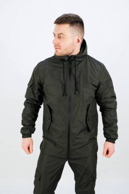 Bir erkek model modern bir taktik kış ceketi ve uyumlu pantolon sergiliyor, açık hava maceraları ve şehir modası için ideal, çok yönlü stok fotoğrafçılığı için mükemmel.