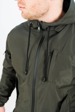 Genç bir adam şık bir zeytin yeşili ceket giyiyor, açık hava aktiviteleri ve şehir ortamları için mükemmel, modern bireyler için pratik işlevsellik ile harmanlama tarzı.