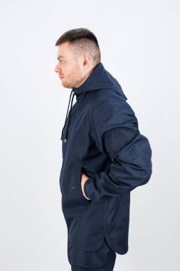 Genç bir adam gösterişli, koyu mavi bir ceketin içinde duruyor. Moda, yaşam tarzı ya da açık hava kıyafetleri için ideal olan şık ve çağdaş bir görünüm sergiliyor.