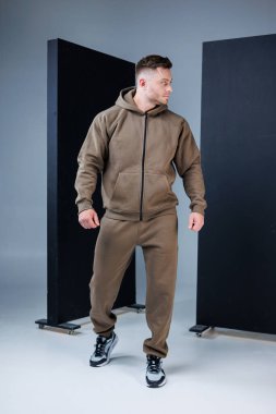 Sportif bir adam modaya uygun kahverengi kapüşonlusunu şık koşucularla eşleştirir. Bunlar yoğun antrenmanlar, spor meraklıları ve günlük kıyafetleri için idealdir.