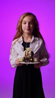 Doğum günü pastasında mum söndüren 8 yaşında tatlı bir kız. Ellerinde pasta tutan neşeli bir kız. Tatlı çocuğun doğum günü.