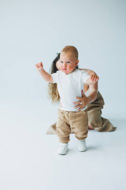 Beyaz bir geçmişi olan genç bir anne bir yaşındaki oğluyla oynuyor. Küçük çocuk ve anne kucaklaşarak gülüyor. Mutlu çocuklu anne..