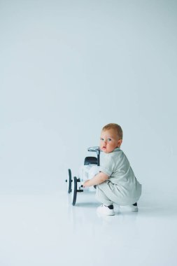 İyi aydınlatılmış ve canlı bir stüdyoda neşeli bir bebek renkli bir oyuncak arabanın yanında çömelmiş, o harika, neşeli aile ve çocukluk anlarını yakalamak için mükemmel bir şekilde kurulmuş.