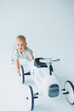 Tişörtlü küçük bir çocuk odada koşuyor ve gülüyor. Küçük bir çocuk mutlu ve gülümsüyor.