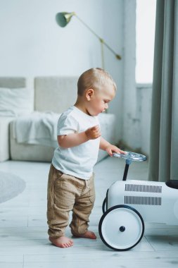 Tişörtlü küçük bir çocuk odada koşuyor ve gülüyor. Küçük bir çocuk mutlu ve gülümsüyor.