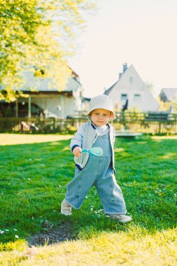 Çimenlerde şık bir tişörtle koşan ve güneşte güneşlenen sevimli bir çocuk. Neşeli bir çocuk gülüşüyle tasasız bir çocukluk. Küçük çocuk eğleniyor ve doğa yürüyüşünün tadını çıkarıyor..