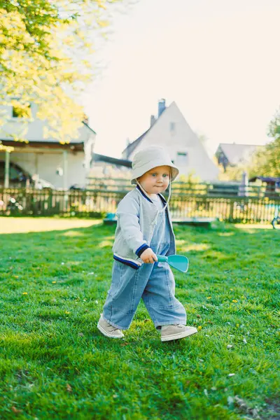 Çimenlerde şık bir tişörtle koşan ve güneşte güneşlenen sevimli bir çocuk. Neşeli bir çocuk gülüşüyle tasasız bir çocukluk. Küçük çocuk eğleniyor ve doğa yürüyüşünün tadını çıkarıyor..