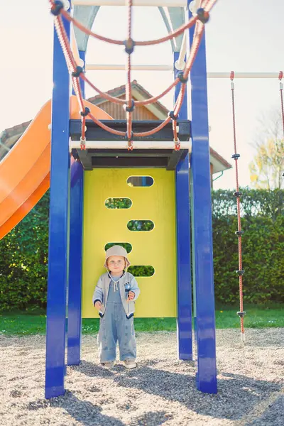 Çocuk parkta koşuyor ve oyun oynuyor. Çocuklar için şık çocuk kıyafetleri. Parkta yeşil çimlerin üzerinde güneşli bir yaz gününün tadını çıkaran 2 yaşında bir çocuk. Doğadaki çocuklar için etkinlikler.