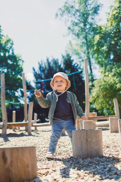 Çocuk parkta koşuyor ve oyun oynuyor. Çocuklar için şık çocuk kıyafetleri. Parkta yeşil çimlerin üzerinde güneşli bir yaz gününün tadını çıkaran 2 yaşında bir çocuk. Doğadaki çocuklar için etkinlikler.