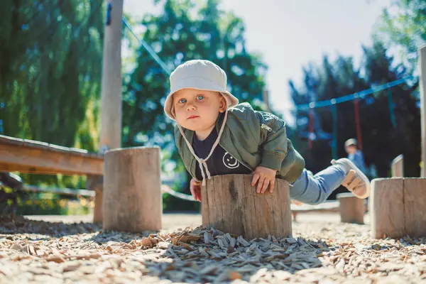 Çocuk parkta koşuyor ve oyun oynuyor. Çocuklar için şık çocuk kıyafetleri. Parkta yeşil çimlerin üzerinde güneşli bir yaz gününün tadını çıkaran 2 yaşında bir çocuk. Doğadaki çocuklar için etkinlikler.