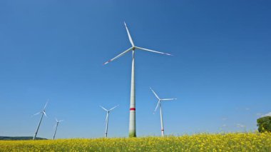 Yeşil alanda rüzgar türbini alanı. Mavi gökyüzü ve yeşil tarım arazisi olan rüzgar tarlası, Avrupa 'da da rüzgar türbini parkı..