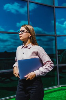 Kendine güvenen genç bir kadın, kariyerinde sürekli ilerlerken profesyonelliğini ve motivasyonunu sergileyerek büyük pencerelerde duruyor.