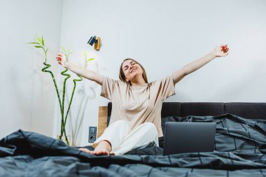 Güzel stili yatak odasında neşeli bir kadın canlı bitkilerin ve modern dekorun arasında rahatlık ve sükunet saçan bir atmosfer yaratıyor.