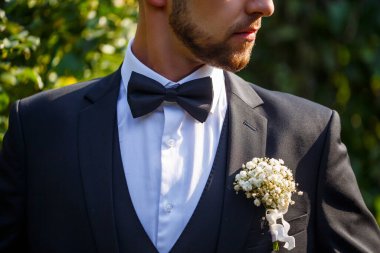 Resmi bir takım elbise ve şık bir papyon giymiş seçkin bir adam cebine güzelce sıkıştırılmış canlı bir çiçekle süslenir ve biraz cazibe katar.