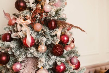 Canlı pembe ve kırmızı süslemelerle süslenmiş güzel dekore edilmiş bir Noel ağacı, sıcak, samimi ve davetkar bir ortamda büyüleyici bir tatil atmosferi yaratır.