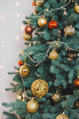 Parıldayan beyaz ışıklarla çevrili, altın ve kırmızı süslemeli güzel dekore edilmiş bir Noel ağacı, tatiller için sıcak ve şenlikli bir atmosfer yaratıyor.