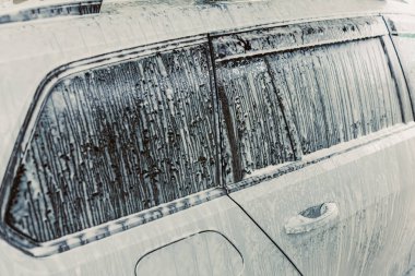 Bir araba penceresinin bu yakın çekiminde yağmur damlaları ve sabun izleri, yağmurlu bir sürücünün özünü yakalamak, otomotiv detaylarını, hava durumunu ve doğal güzelliklerini vurgulamak,