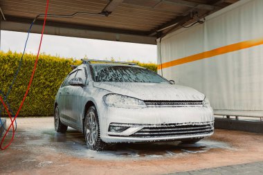 Modern bir araba yıkama, köpükle kaplı, temiz ve profesyonel bir çamaşır servisi ortamı sunan parlak bir araç yakalar.