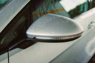 Arabaların yakın çekimlerinde, ayna kenarında su damlacıkları sergilenirken, parlak tasarım ve modern estetiği ön plana çıkarırken, ışık da araçların lüks çekiciliğini artırıyor.