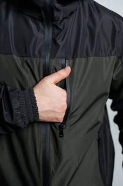 Açık hava spor aktiviteleri ve günlük giysiler için mükemmel tasarlanmış zarif bir spor ceketin fermuar cebini gösteren bir adamın yakın plan çekimi.