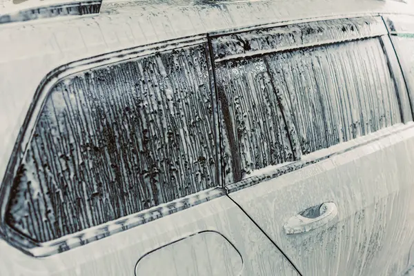 Bir araba penceresinin bu yakın çekiminde yağmur damlaları ve sabun izleri, yağmurlu bir sürücünün özünü yakalamak, otomotiv detaylarını, hava durumunu ve doğal güzelliklerini vurgulamak,