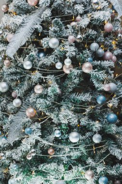 Göz kamaştırıcı bir Noel ağacı, pırıl pırıl ışıklar ve pastel renklerle süslenmiş zarif süsler, bayram kutlamaları için mükemmel.