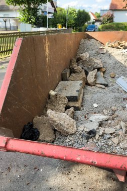 Dolu bir atık konteynırında, yenileme ve inşaat projeleri sırasında kentsel atık yönetimi sorunları vurgulanarak çeşitli inşaat atıkları sergileniyor.